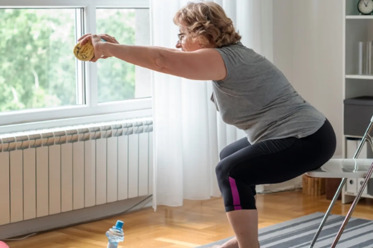 Older woman doing balance and strength exercises at home to help prevent falls
