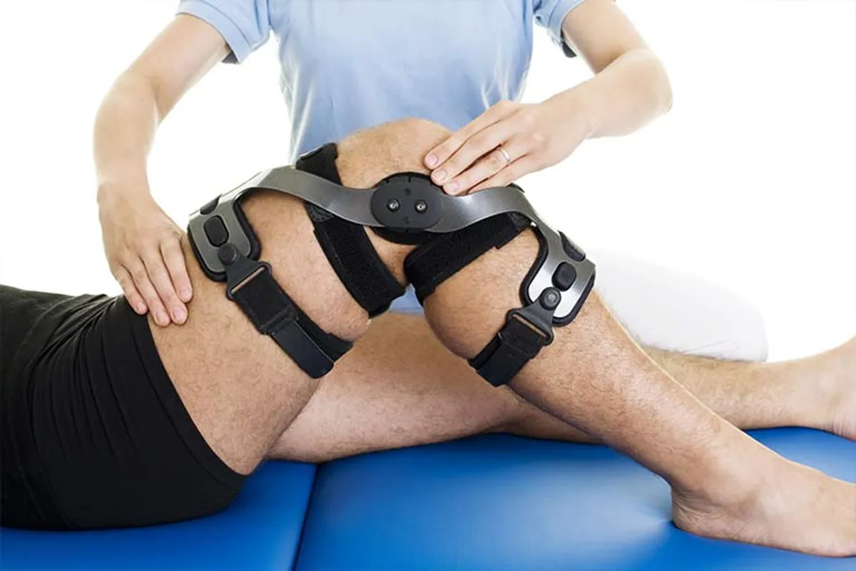 Physiotherapist guiding knee replacement rehab exercises in a client's home